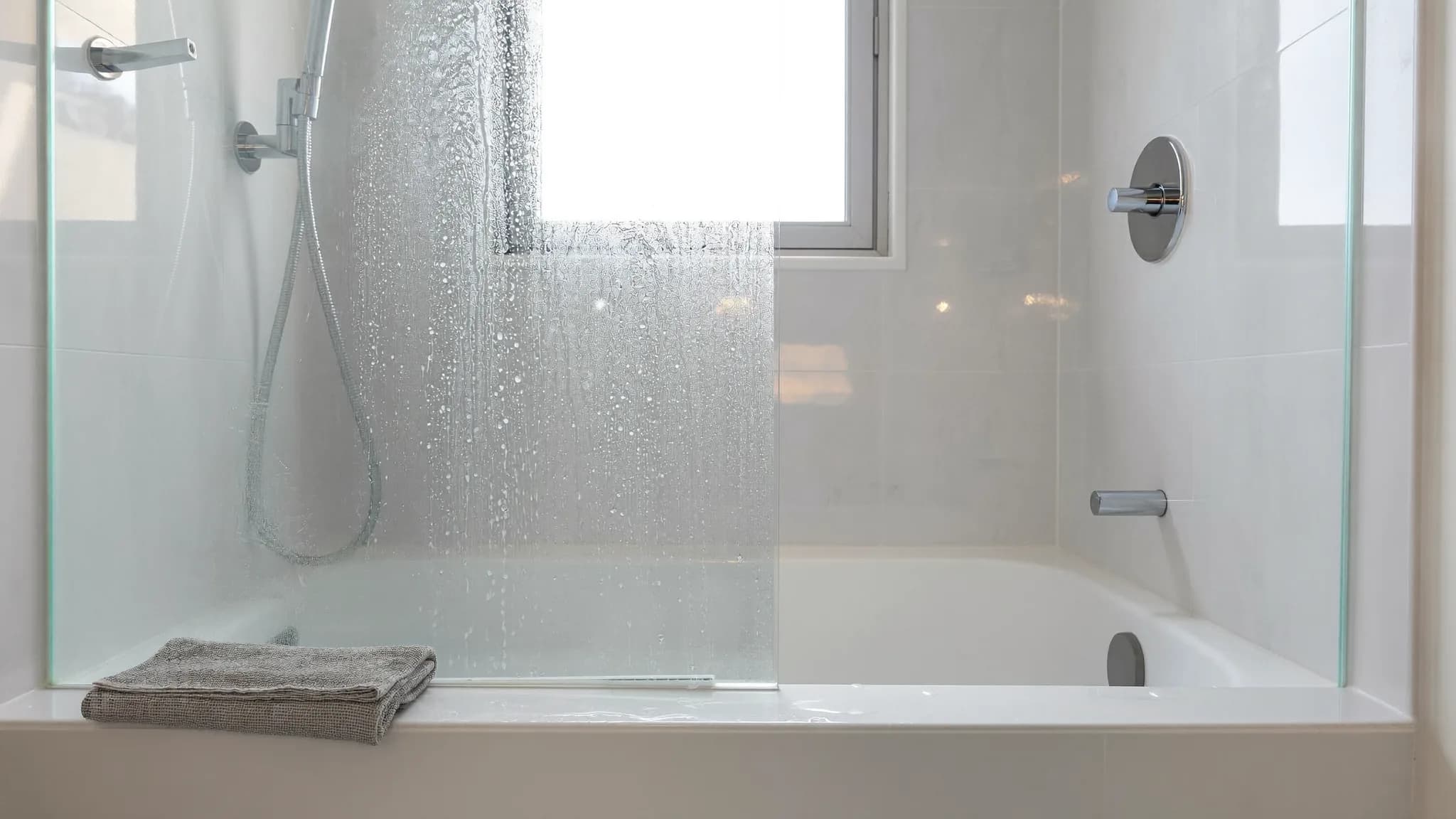 Shower glass half cleaned to show how to remove hard water stains in a Las Vegas bathroom