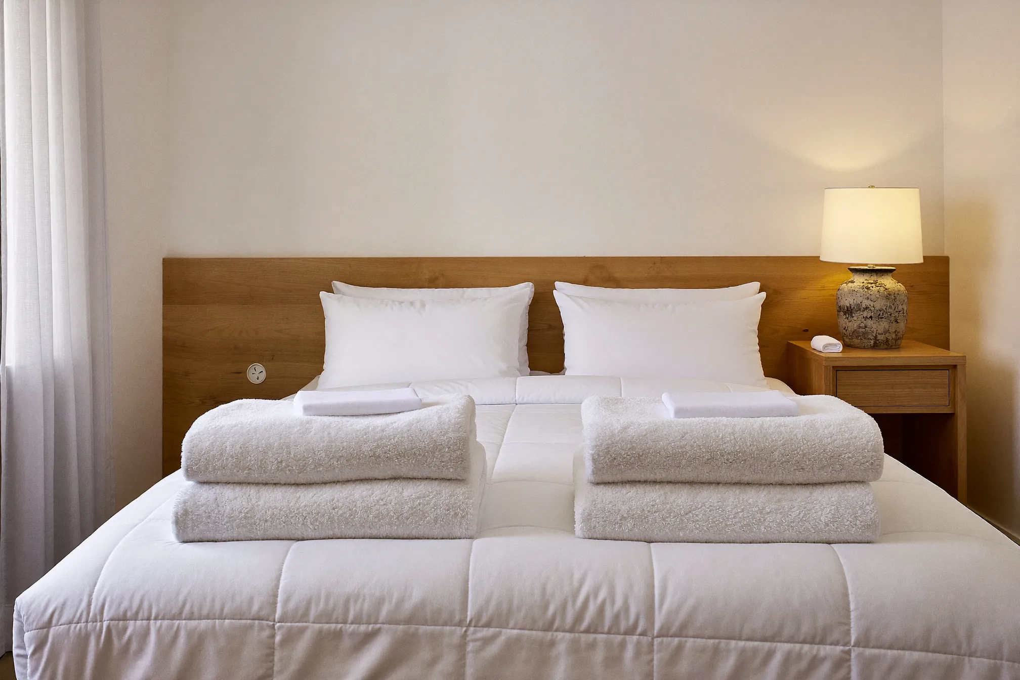 Freshly made bed with folded towels ready for the next Airbnb guest