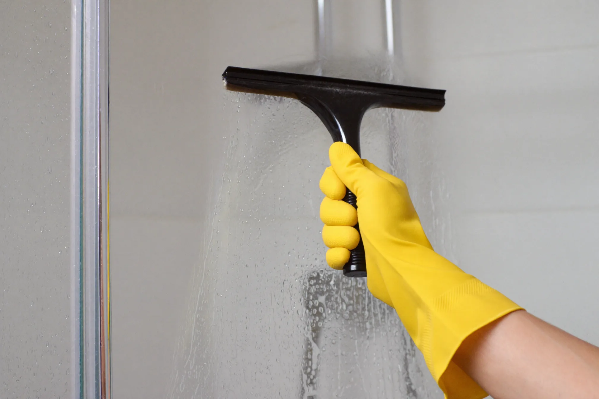 Squeegee drying shower glass to prevent new hard water spots